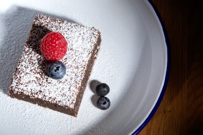 Brownie mit Puderzucker und Früchten auf einem Teller, von oben fotografiert